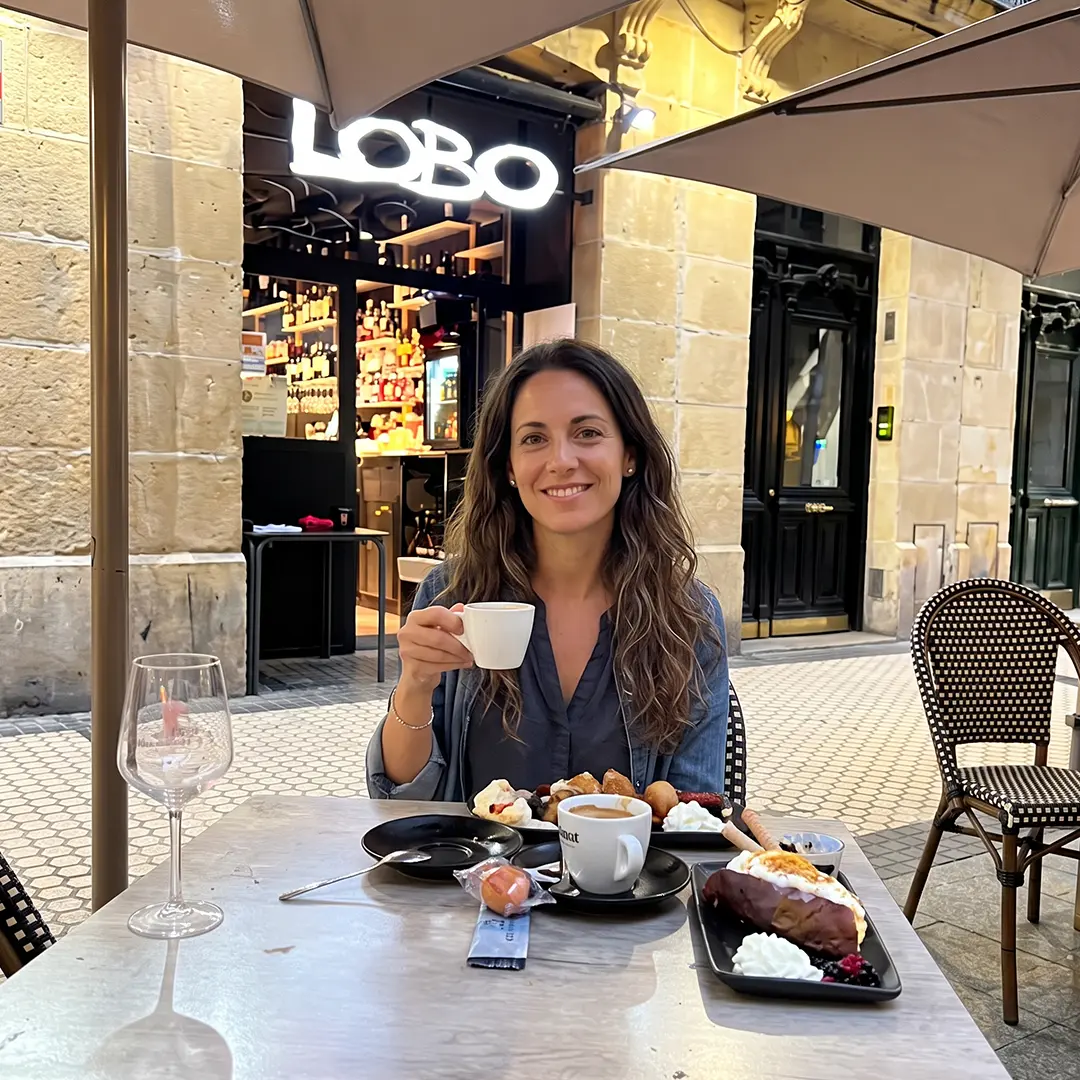 Clienta sonriendo con un café y postres en la terraza de LOBO